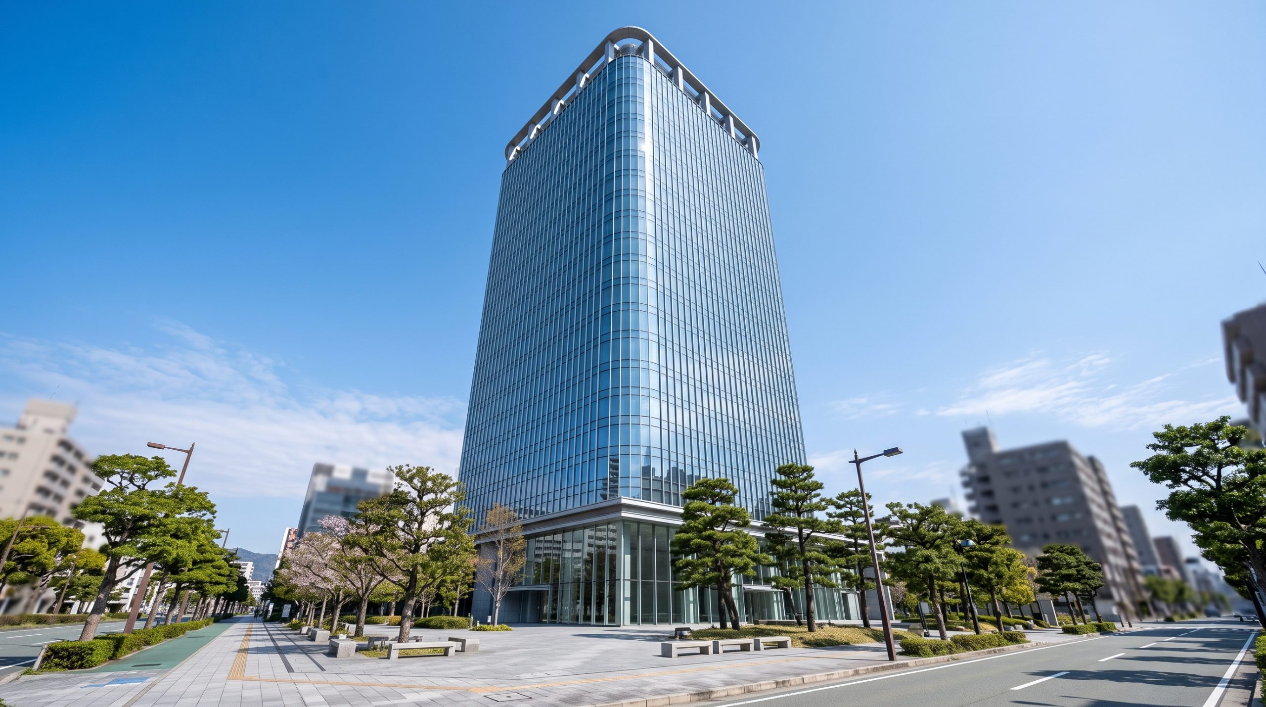 青空の下に建つガラス張りの高層ビル。ホテルや大規模施設の外観をイメージした写真。